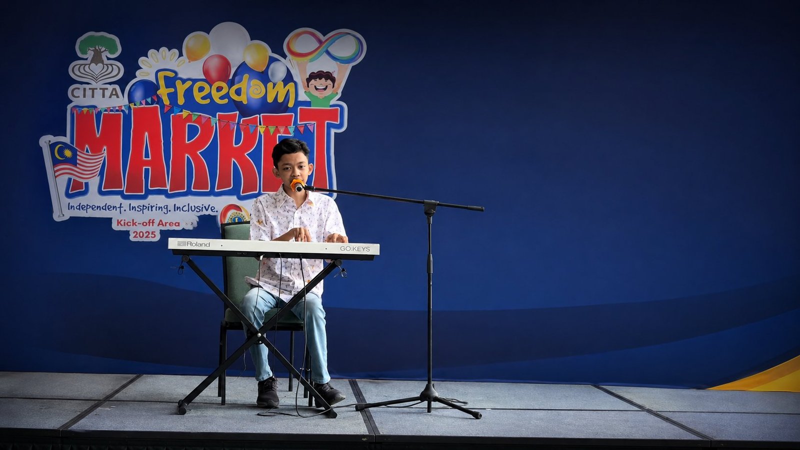 Raees, an autistic pianist, singing and playing keyboard on stage at the CITTA Freedom Market community event