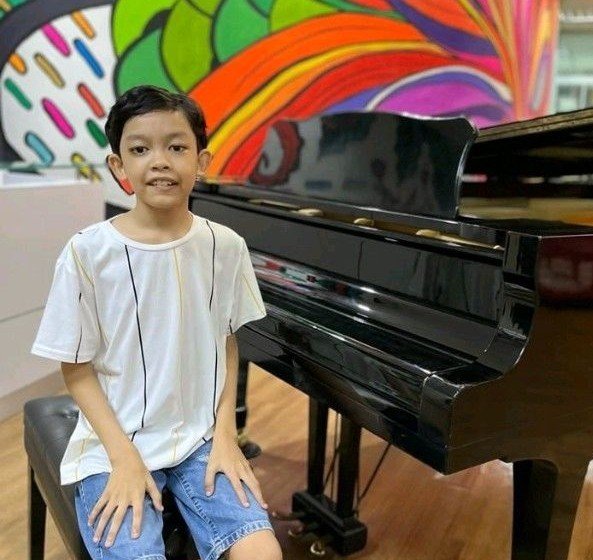 Raees, an autistic pianist, sitting at a grand piano in front of a colorful mural
