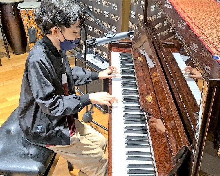 Raees, an autistic pianist, performing on stage at a music studio wearing a mask